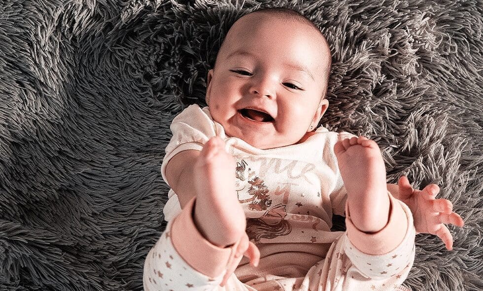 Happy baby lying on a fuzzy blanket.