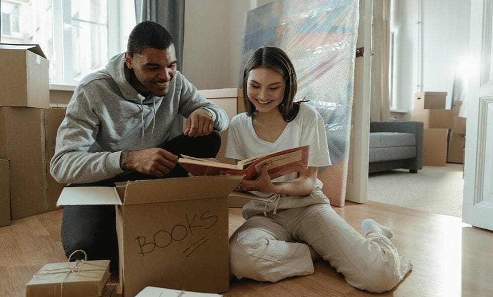 A man and woman sitting on the floor reading books.