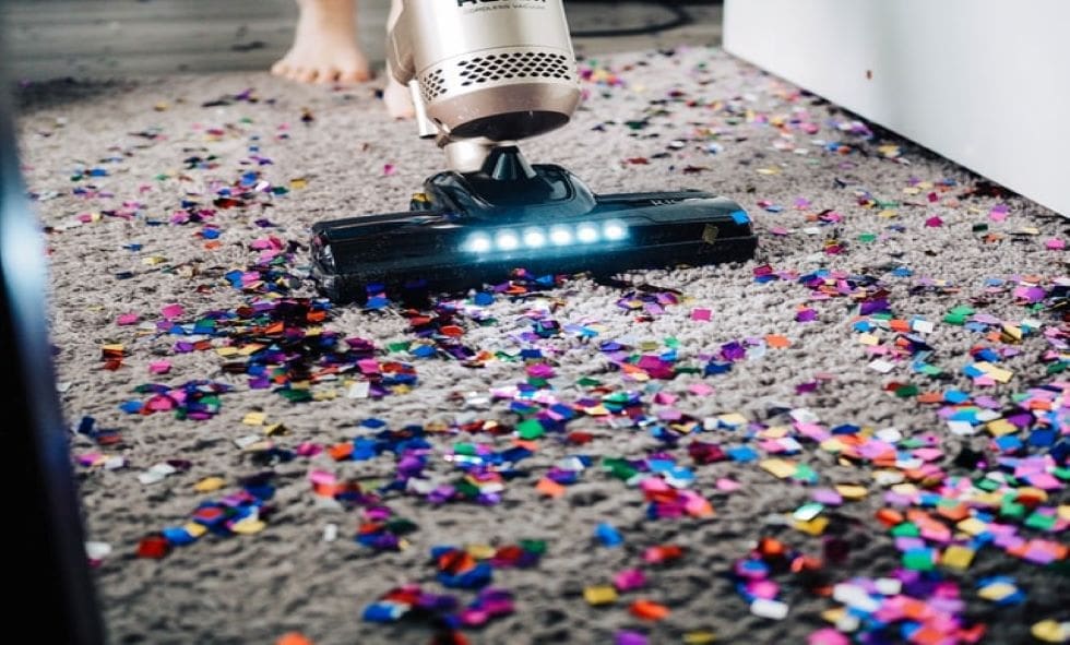 A person using a vacuum to clean up confetti.