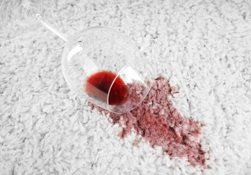 Overturned glass and spilled exquisite red wine on soft carpet remove carpet stains