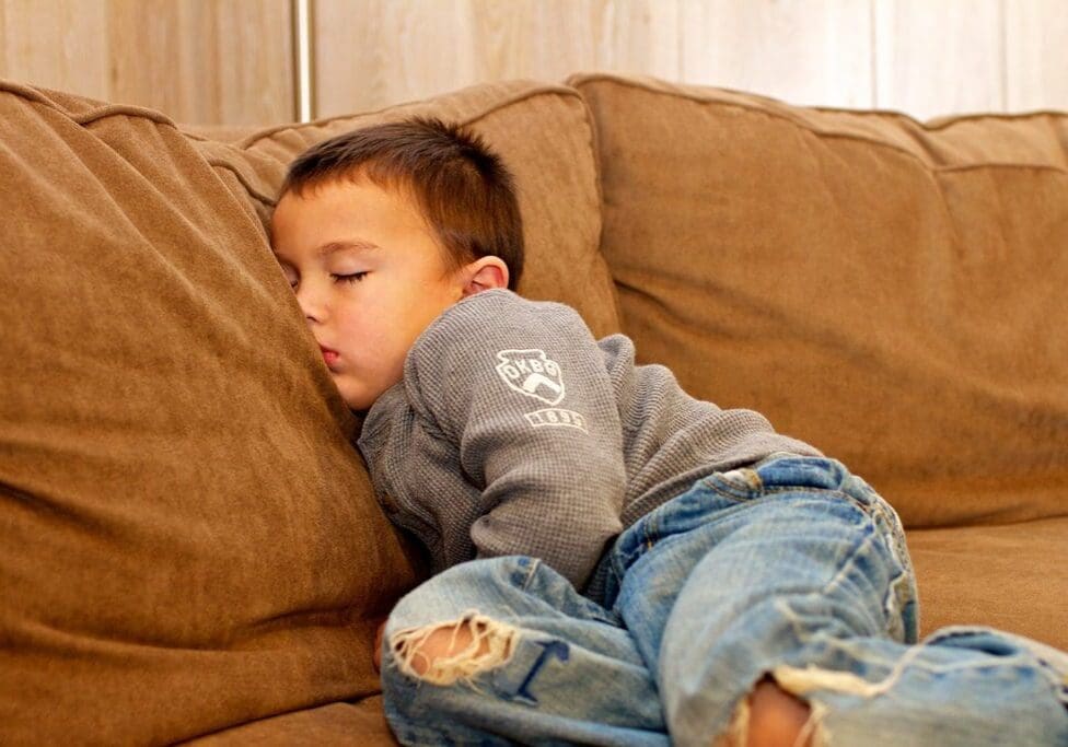 A young boy is sleeping on the couch