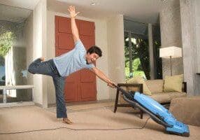 A man is doing a trick with a vacuum cleaner.
